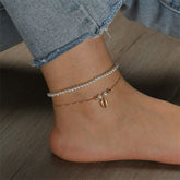 A pair of stylish anklets adorned with pearls and gold chains, highlighting a pearl and 18K gold-plated shell charm.