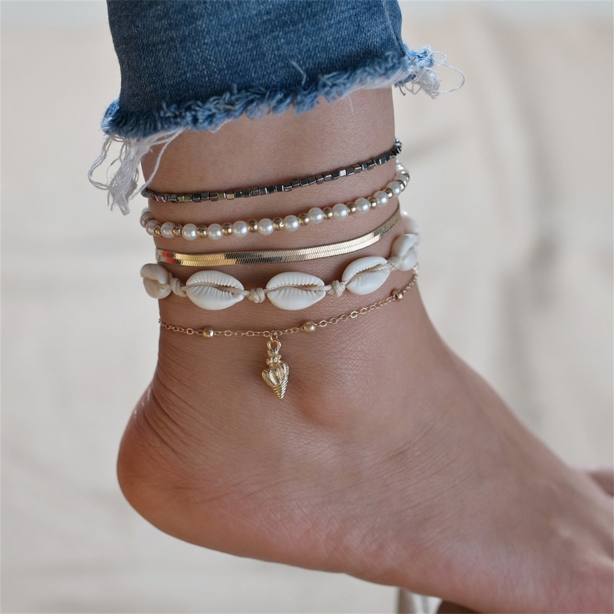 Three elegant gold and black anklets adorned with shells and pearls, showcasing a luxurious 18K gold-plated design.