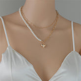 An 18K gold-plated necklace adorned with a heart charm and a pearl, showcasing a refined and elegant design.