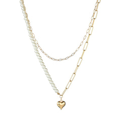 A layered pendant necklace in 18K gold plating, featuring a heart charm and a lustrous pearl for a chic appearance.