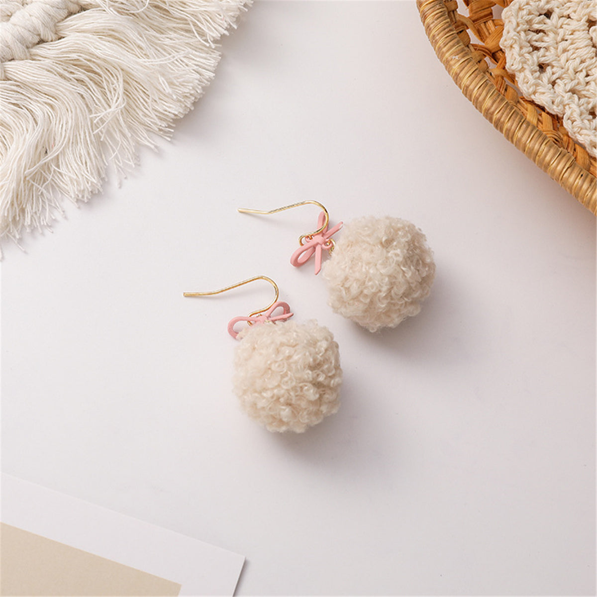 Elegant 18K gold-plated earrings featuring fluffy white pom poms and a charming pink bow for a stylish touch.