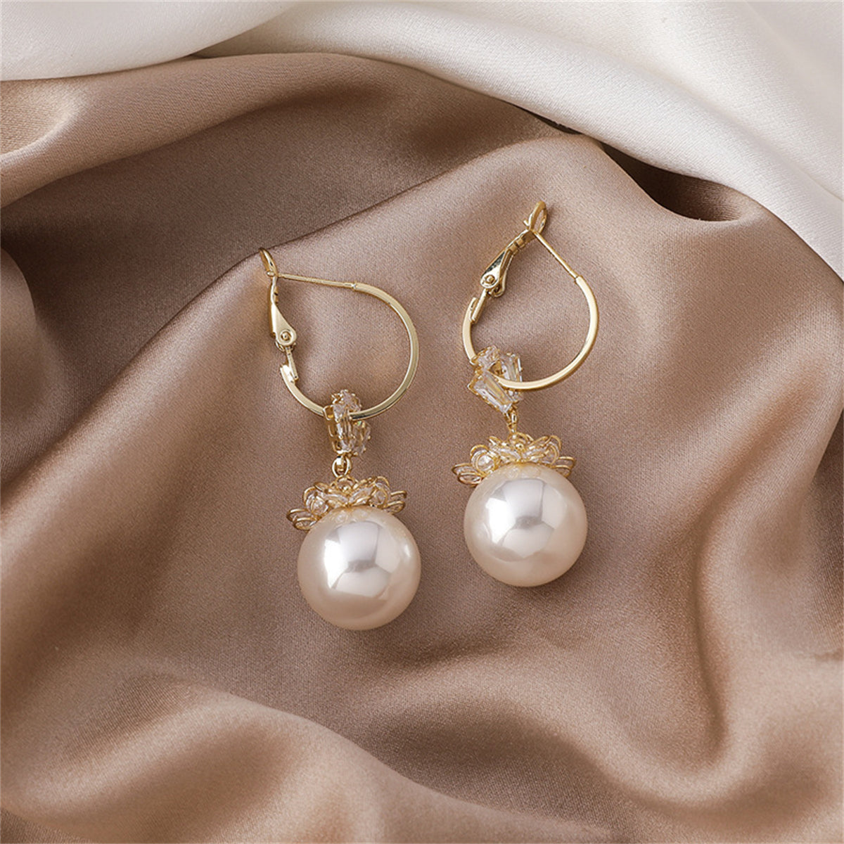 Elegant 18k gold-plated floral huggie earrings featuring white pearls and sparkling cubic zirconia crystals.