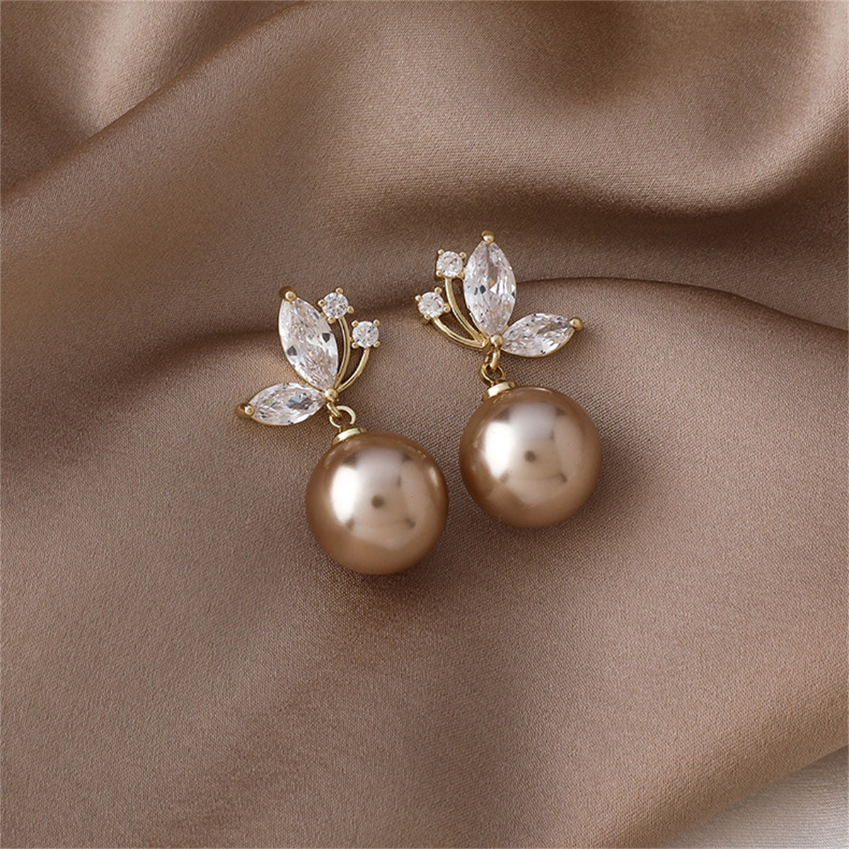 Stunning champagne pearl earrings with a butterfly design, embellished with white pearls and cubic zirconia.