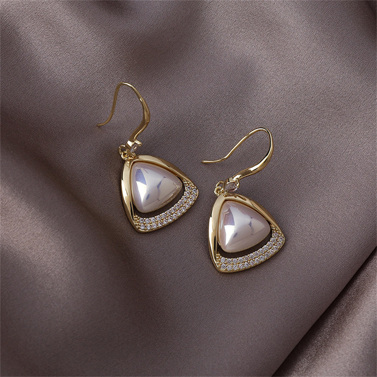 Gold-plated open-triangle drop earrings featuring white cubic zirconia stones and a pearl accent.