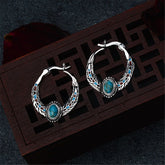 Turquoise and silver-plated feather hoop earrings featuring turquoise stones and intricate silver detailing.