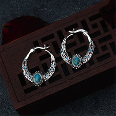 Turquoise and silver-plated feather hoop earrings featuring turquoise stones and intricate silver detailing.