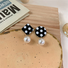 Mismatched drop earrings with black and white polka dots and a pearl accent, adding a playful touch to any outfit.