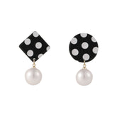 Black and white polka dot drop earrings featuring a pearl, showcasing a geometric mismatched design.
