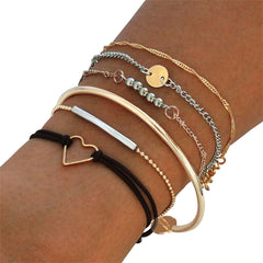 A stylish stack of 18K gold-plated and silver-plated bracelets featuring a charming heart pendant.