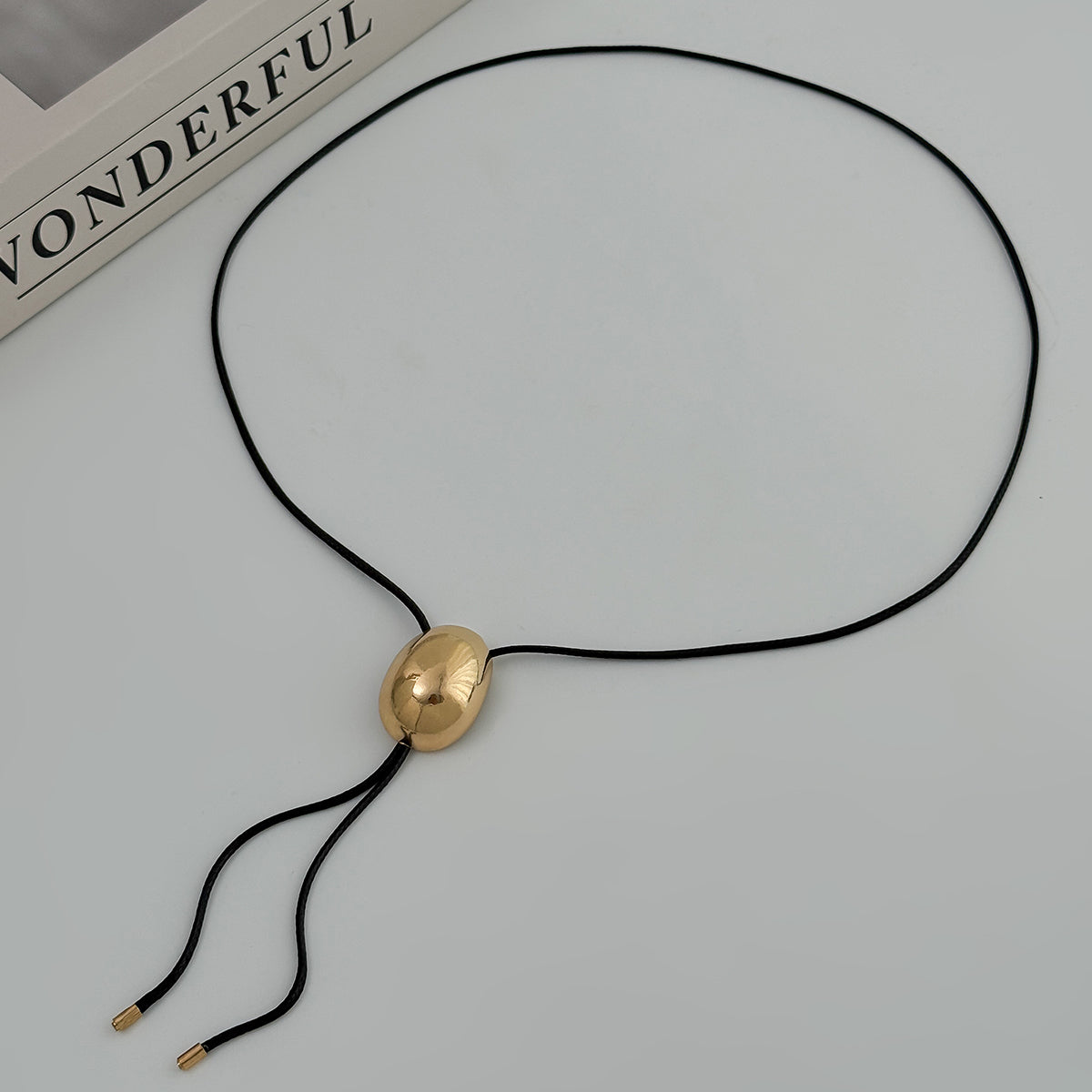Black Polyster and Goldtone Oval Tassel Necklace, botanical inspired, detail close-up