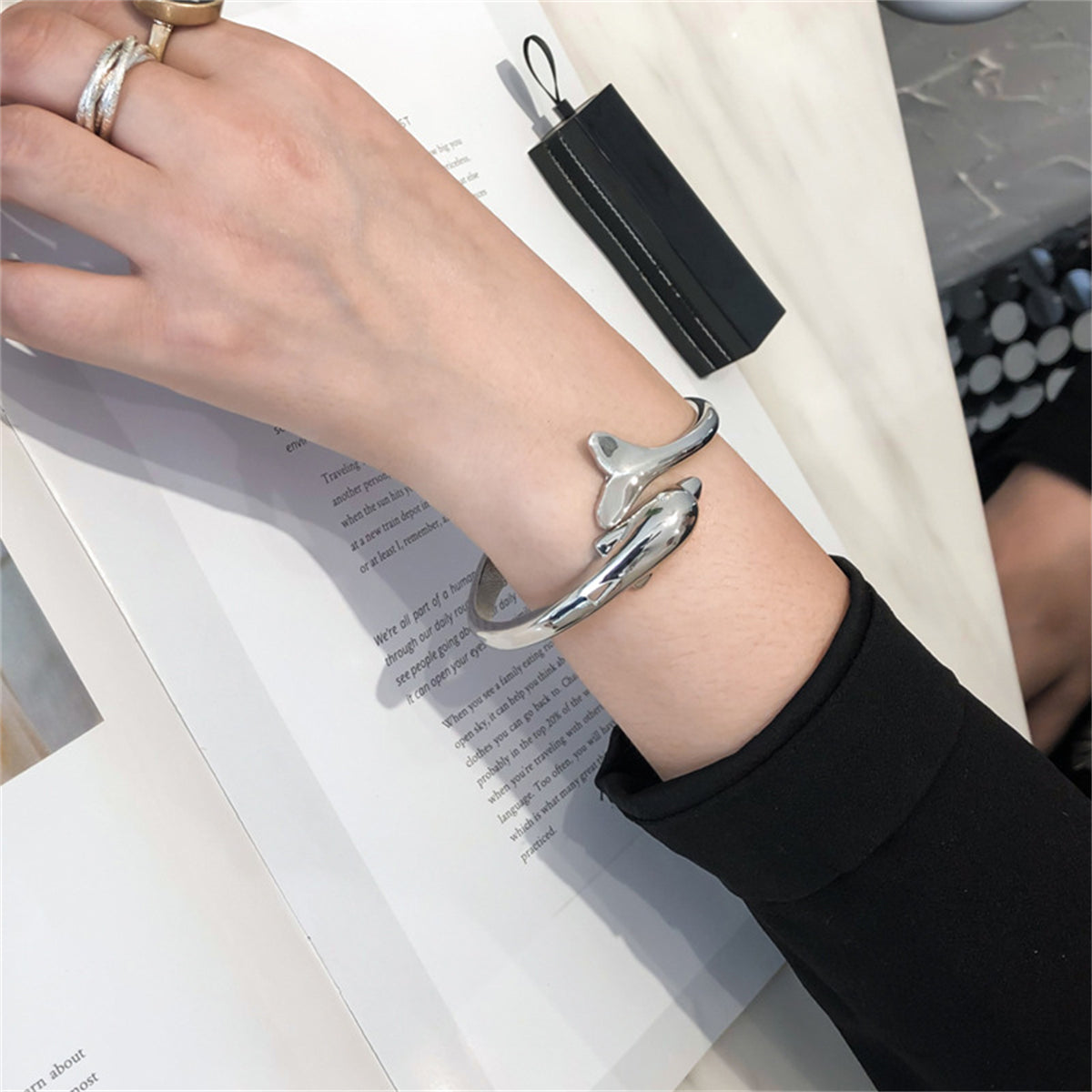 A silver-plated dolphin design bangle, elegantly hinged, reflecting a sophisticated style inspired by the ocean.