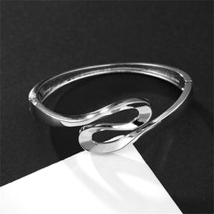A silver-plated ribbon bangle characterized by its smooth, curved design, ideal for enhancing any jewelry collection.