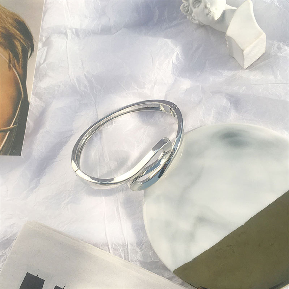 A chic silver bracelet with a flowing curved design, this silver-plated ribbon bangle offers a touch of elegance.
