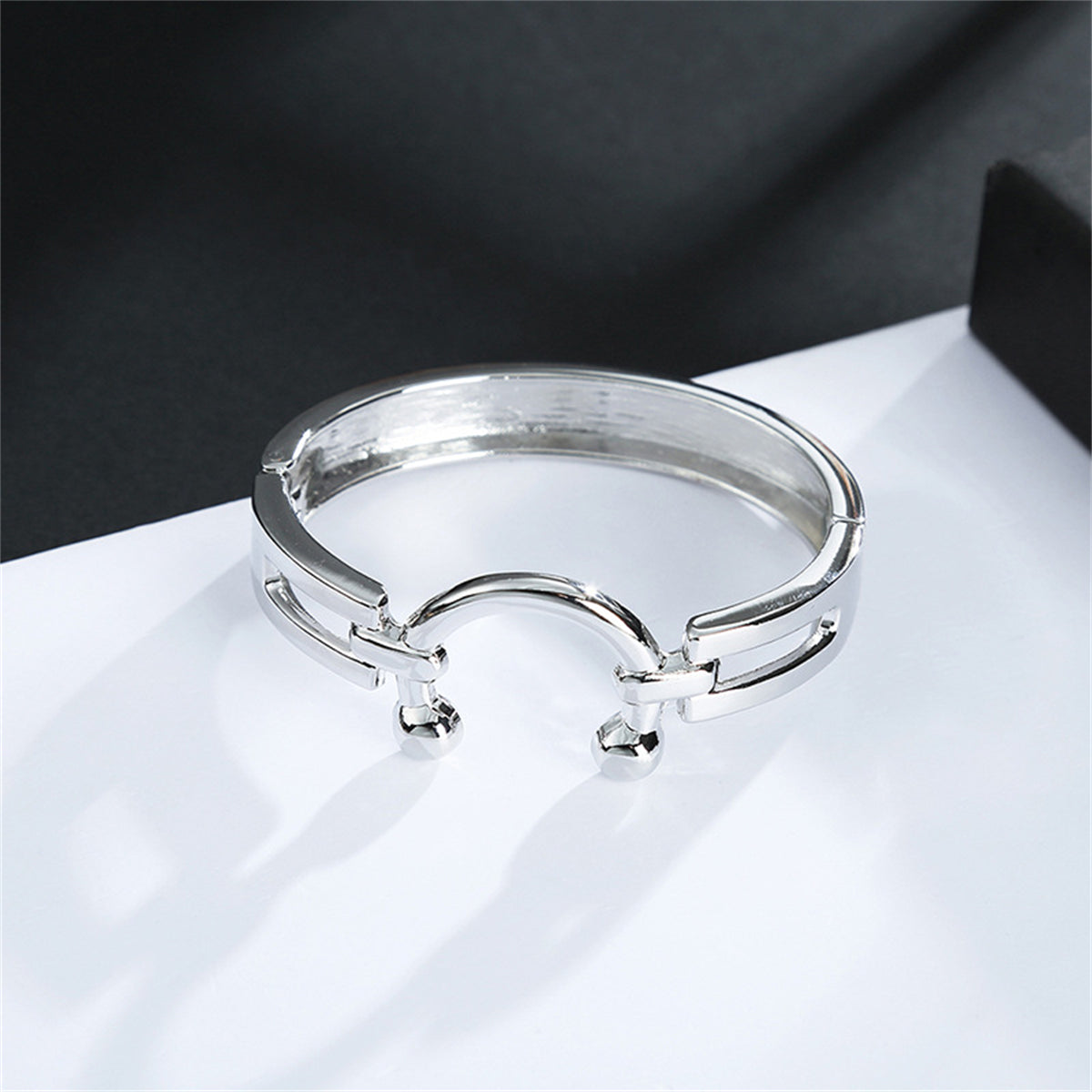 A sleek silver ring styled as a saddle bangle, embellished with two round balls on each side for a modern touch.