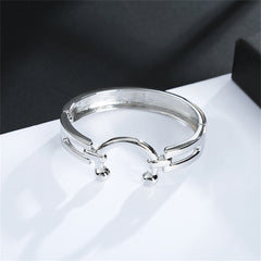 A sleek silver ring styled as a saddle bangle, embellished with two round balls on each side for a modern touch.