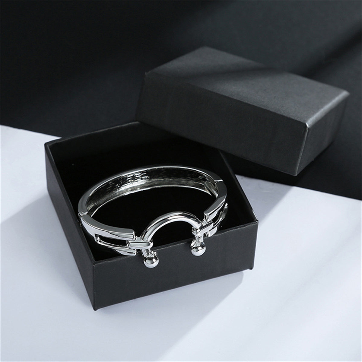Silver-plated saddle bangle featuring a ring with two side balls, combining elegance and contemporary design.