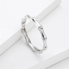 Elegant white gold band featuring diamonds on the sides, alongside a cubic zirconia and silver-plated bamboo bangle.
