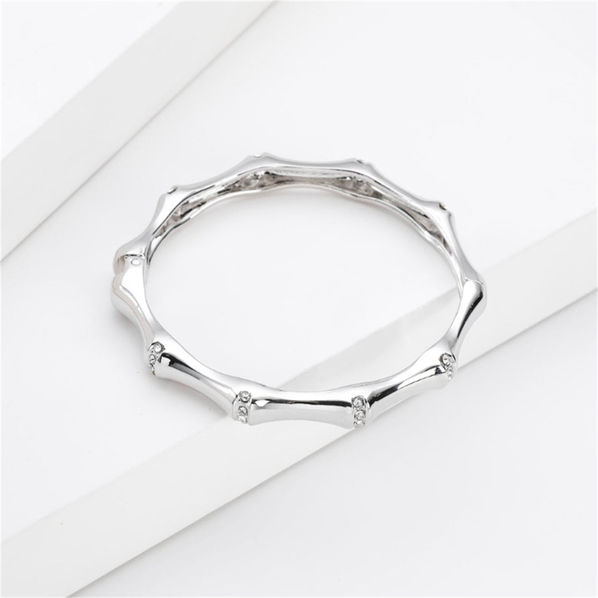 White gold band embellished with side diamonds, accompanied by a cubic zirconia and silver-plated bamboo bangle.