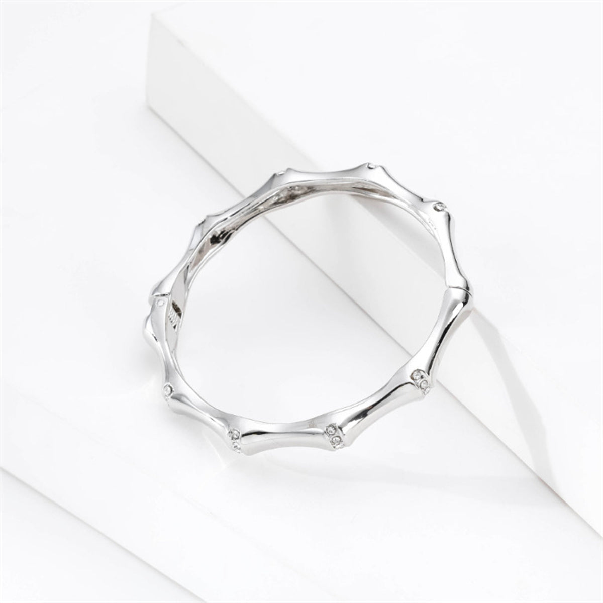 A sophisticated white gold band with diamonds on the sides, together with a cubic zirconia and silver-plated bamboo bangle.