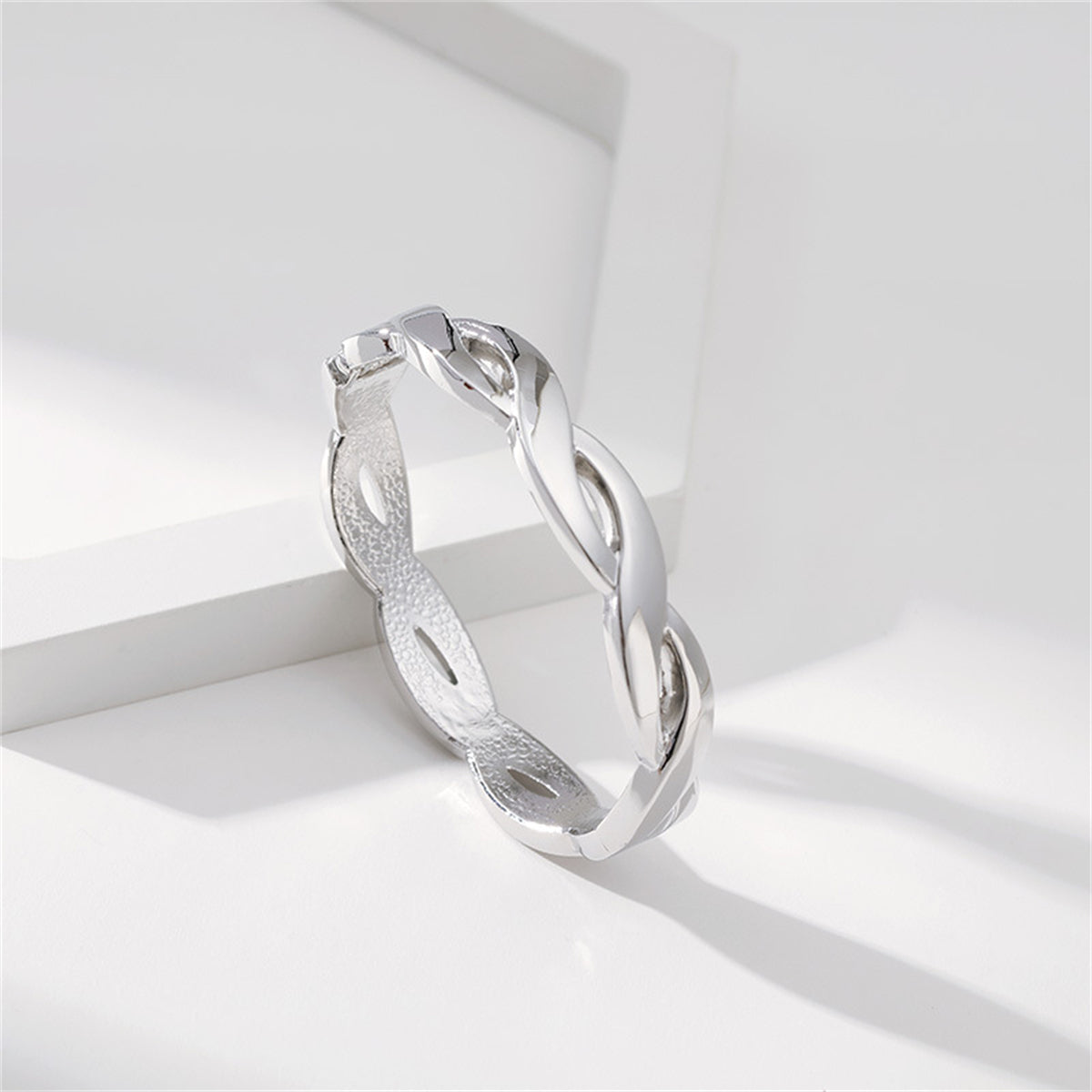 A silver-plated bangle with a unique twisted design, inspired by a silver-plated twine bangle, highlighting its intricate details.