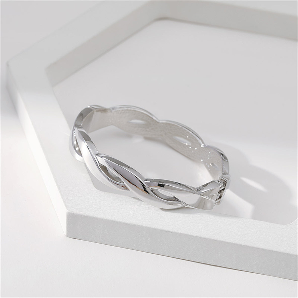 A silver-plated characterized by a twisted design, similar to a silver-plated twine bangle, exemplifying refined artistry.