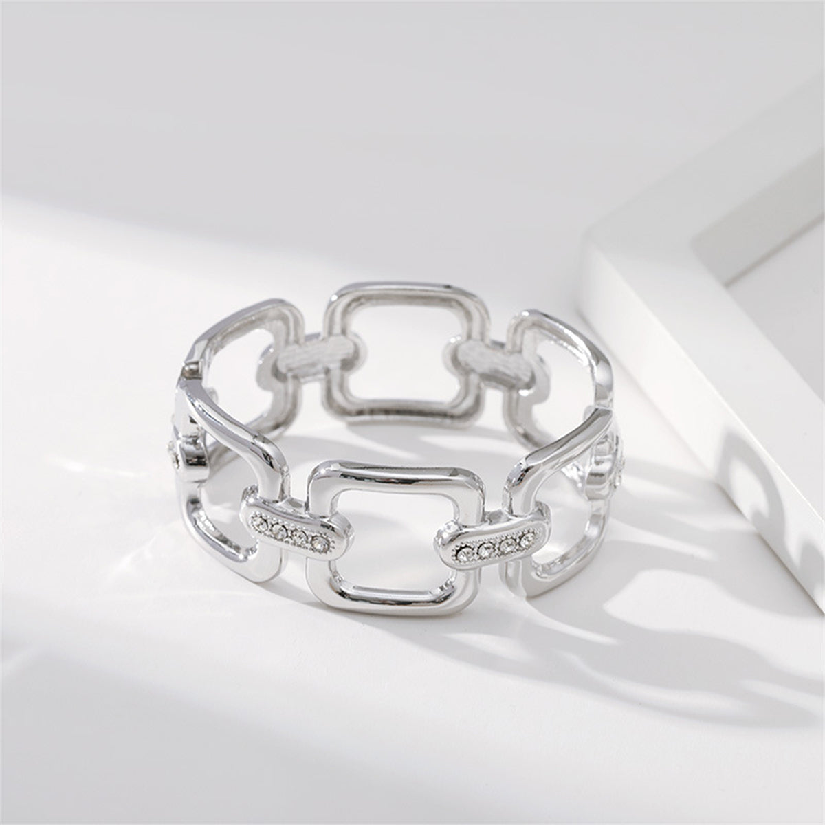 A refined silver-plated and diamond bracelet, incorporating a cubic zirconia and silver-plated open square bangle element.