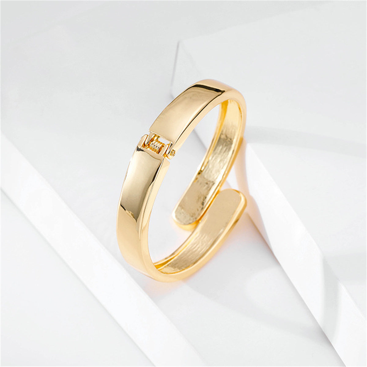 Luxurious 18K gold-plated bangle bracelet designed with a bypass hinge and two stylishly curved edges for a contemporary flair.