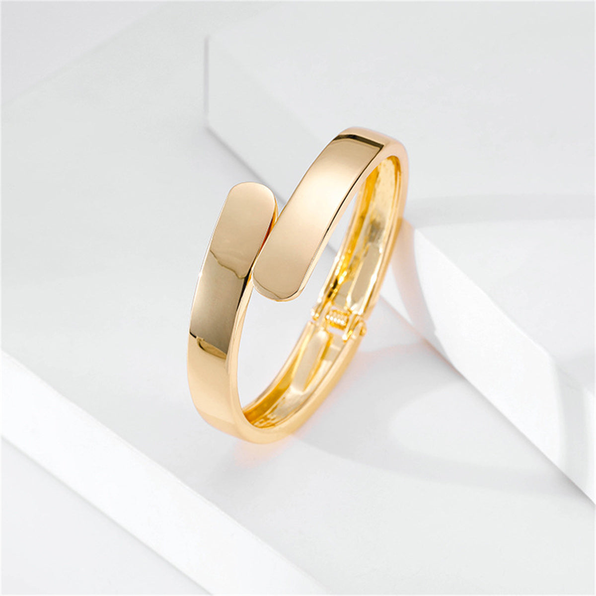 Fashionable 18K gold-plated bangle bracelet with a sleek bypass hinge and two smooth, curved edges for a sophisticated touch.