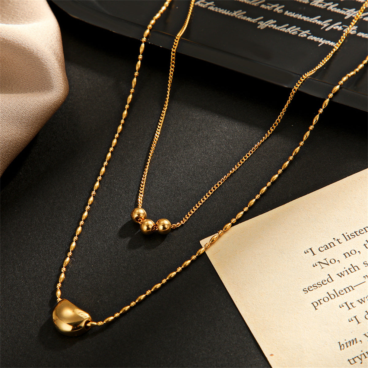 Two layered necklaces in 18K gold plating, each showcasing a charming bead, perfect for a trendy and sophisticated look.