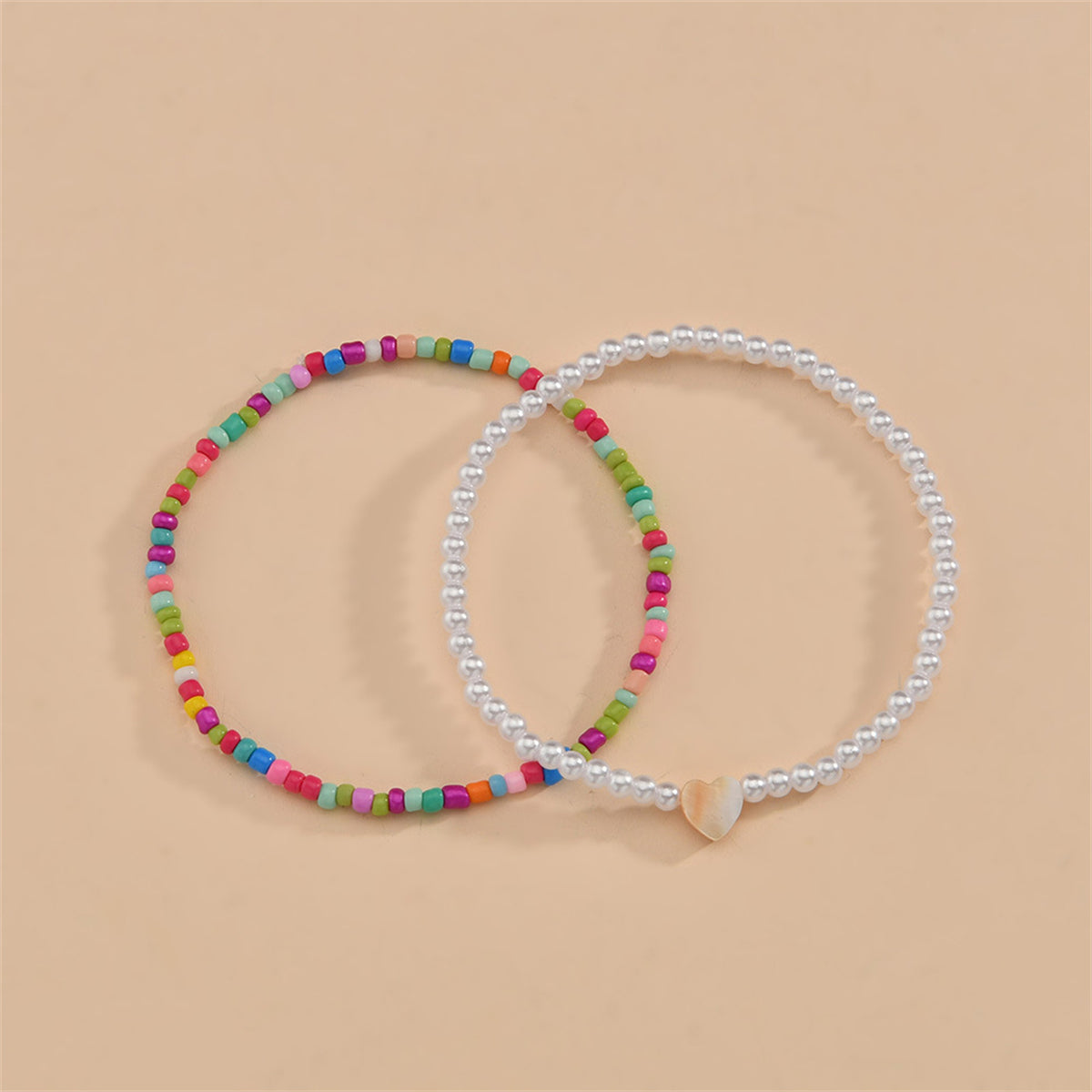  Two vibrant anklets with colorful beads and a heart charm, designed as a red multicolor howlite anklet set.