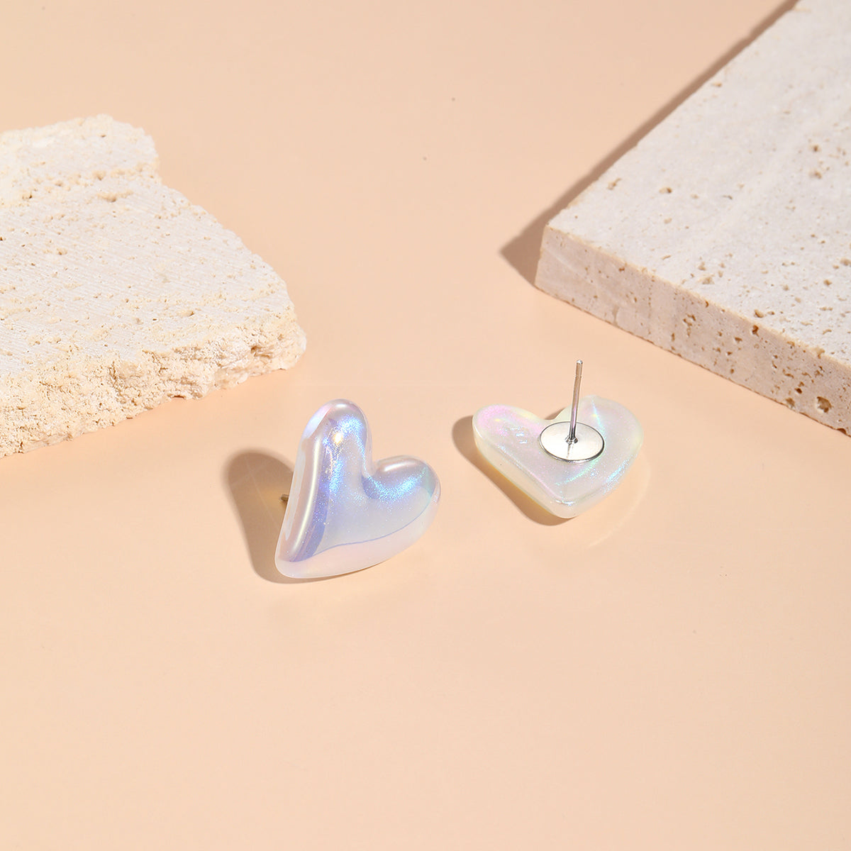 White heart-shaped earrings featuring pearl and silver plating, designed as tilted studs for a chic appearance.