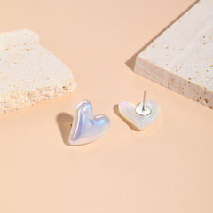 White heart-shaped earrings featuring pearl and silver plating, designed as tilted studs for a chic appearance.