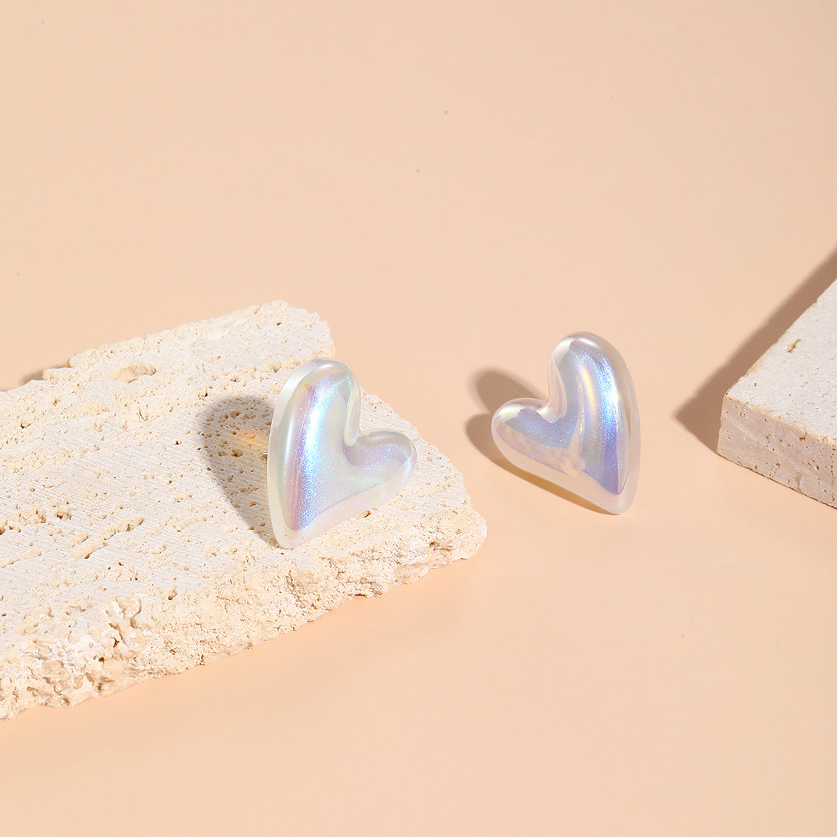 A stylish pair of tilted heart stud earrings in white, crafted from pearl and silver plating for a sophisticated touch.