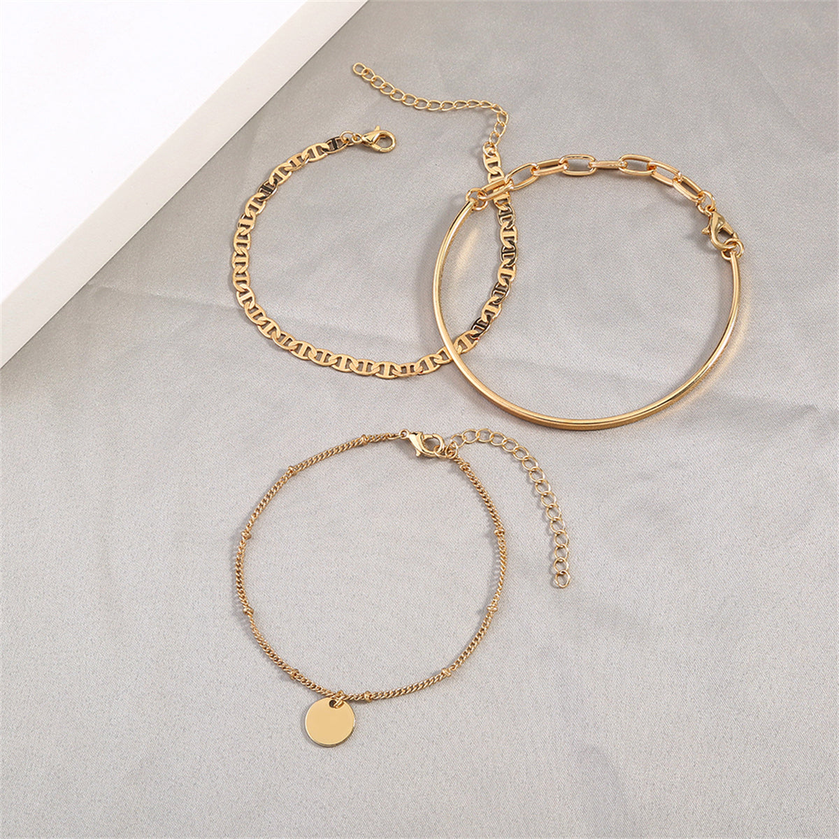 Three exquisite gold bracelets featuring a disc charm, designed to enhance your style with 18K gold-plated allure.