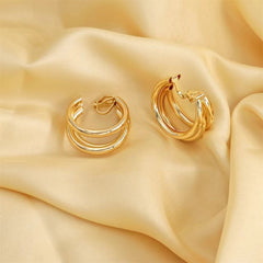 Dazzling 18K gold-plated crisscross hoop earrings elegantly placed on silk fabric, capturing their beauty and sophistication.