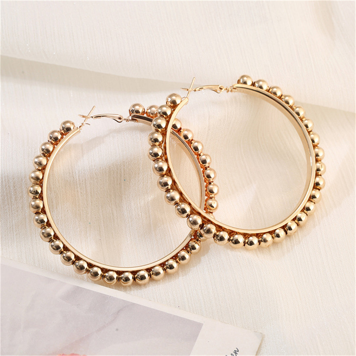 Elegant 18K gold-plated hoop earrings adorned with beautiful beads, perfect for adding a touch of glamour to any outfit.