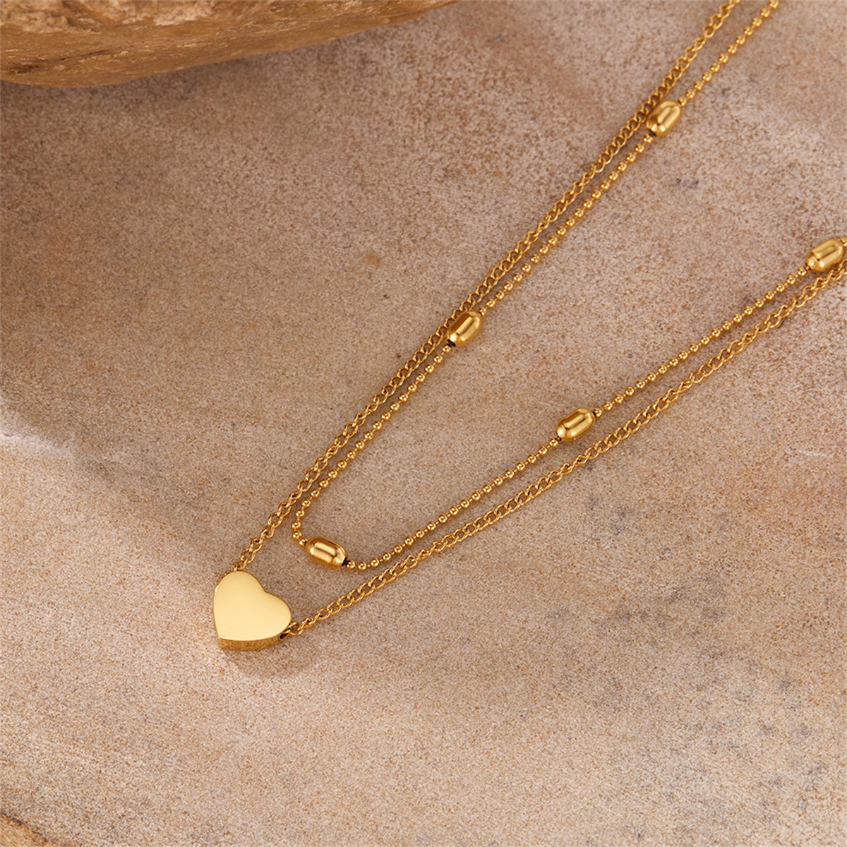 Charming gold chain necklace with a heart charm, crafted from 18K gold-plated beads for a stylish and heartfelt statement.