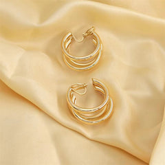 Beautiful 18K gold-plated crisscross hoop earrings on silky fabric, emphasizing their luxurious appeal and intricate design.