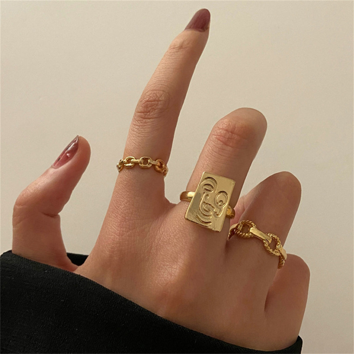 Three elegant gold-plated rings with initials, paired with a stylish chain, perfect for personalized fashion statements.