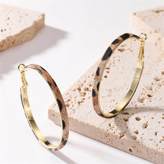 Stylish gold hoop earrings adorned with black and white dots, showcasing a trendy leopard print design.