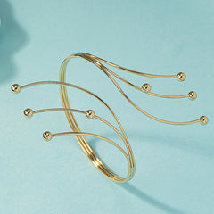 Beautiful 18K gold-plated arm cuff showcasing a unique bypass style with four eye-catching beads for added flair.