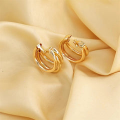 Elegant 18K gold-plated crisscross hoop earrings resting on luxurious silk fabric, showcasing their stunning shine and design.