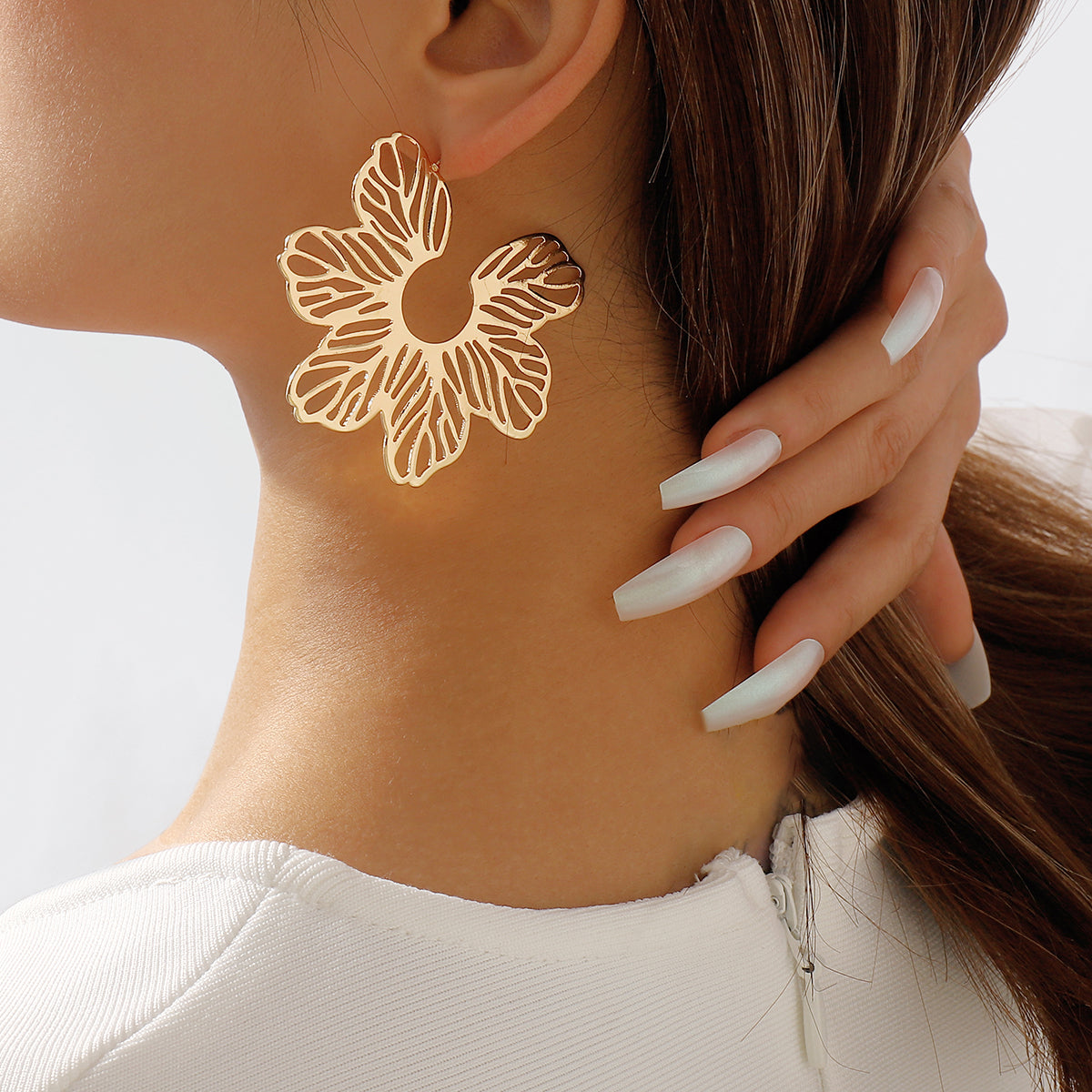 Elegant 18K gold-plated cutout flower huggie earrings on a pristine white background, showcasing their stunning design.