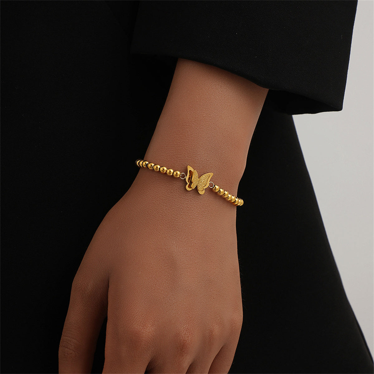 Elegant 18K gold-plated butterfly bracelet adorned with charming beads, perfect for adding a touch of luxury to any outfit.