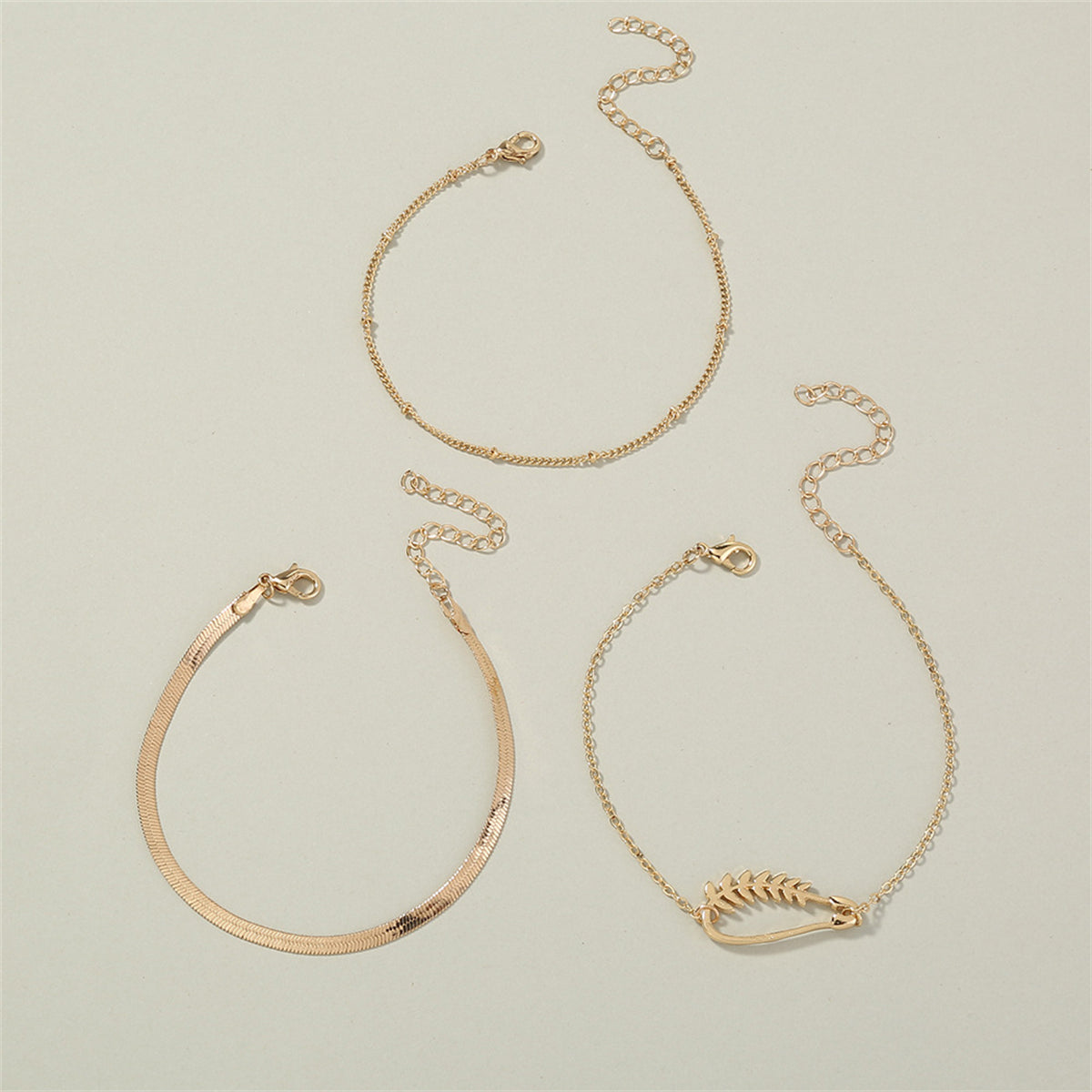 A chic trio of 18K gold-plated bracelets with a chain and leaf charm, perfect for adding a touch of nature-inspired elegance.