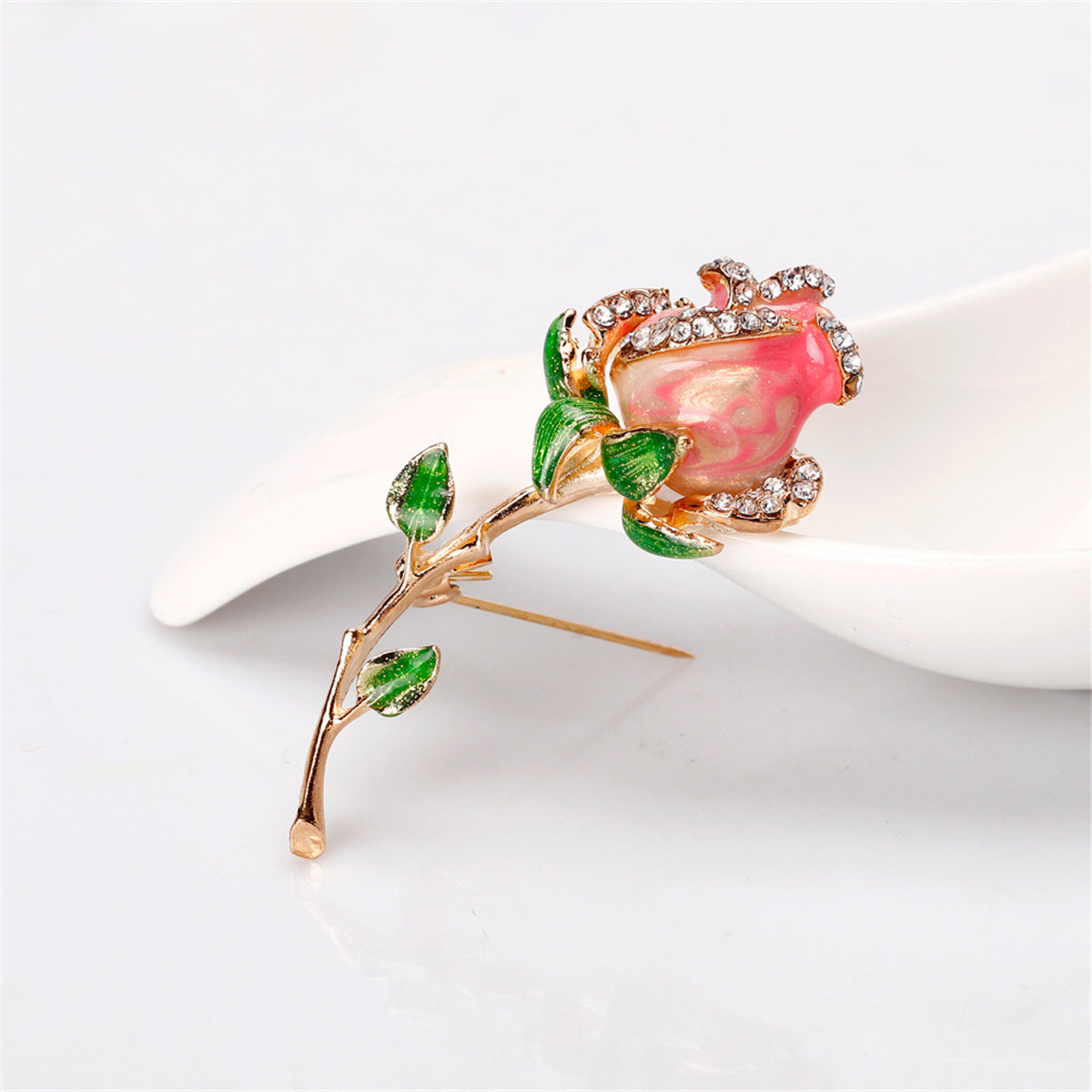 Exquisite pink rose brooch adorned with green leaves, crafted in 18K gold-plated and cubic zirconia elegance.
