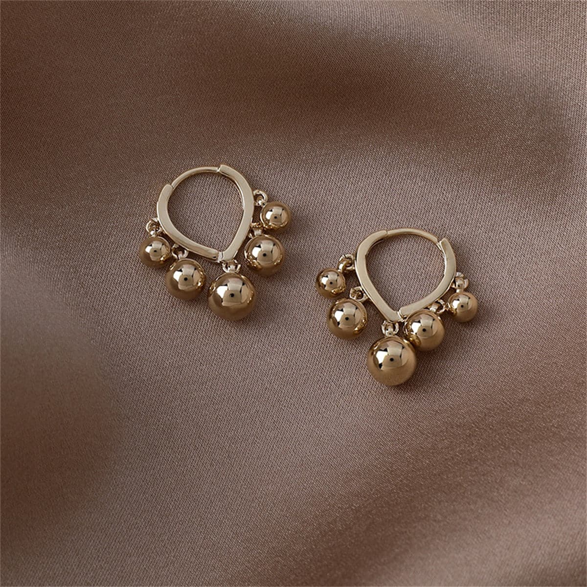 Stunning 18K gold-plated huggie earrings with ball tassels, adding a touch of glamour to your jewelry collection.