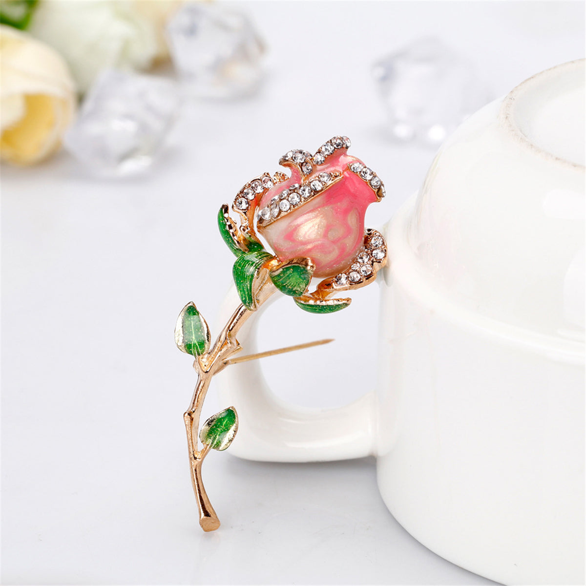 Opulent pink rose brooch with verdant green leaves, featuring exquisite 18K gold plating and dazzling cubic zirconia.