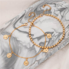 A chic duo of gold chain anklets with charms, featuring a luxurious 18K gold-plated coin tassel bead design.