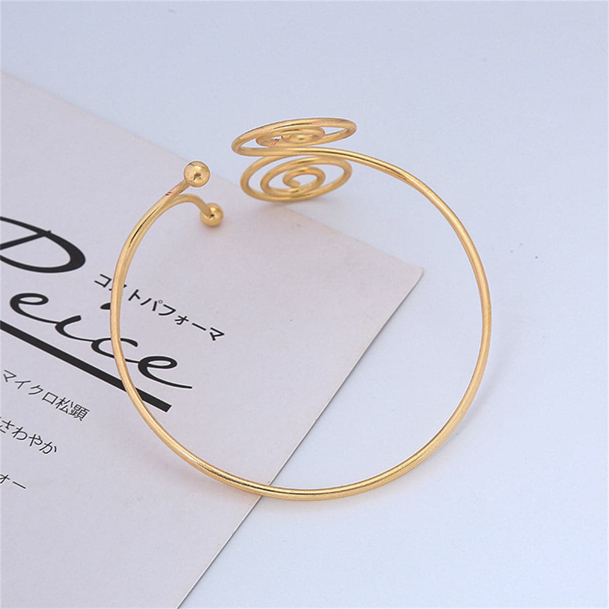 Dazzling gold-plated spiral arm cuff with a double swirl design, a must-have accessory for any fashion enthusiast.